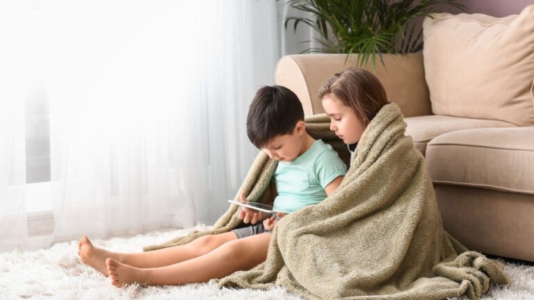 Dzieci oglądające tablet pod kocem