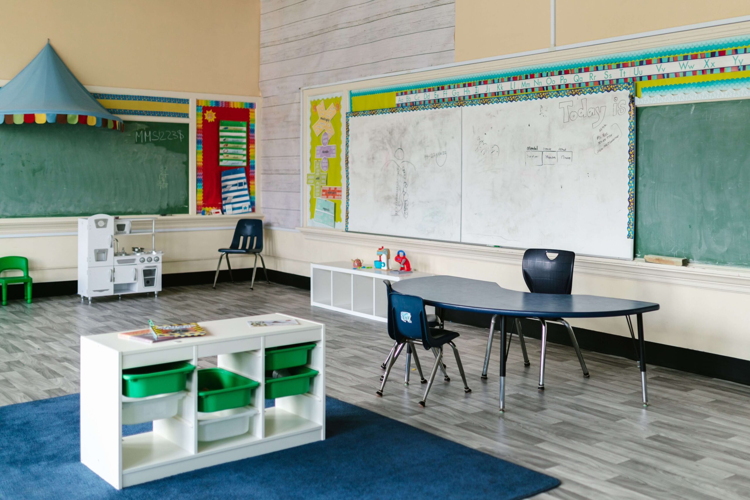 Sala przedszkolna podzielona na strefy z niskimi regałami i oznaczeniami